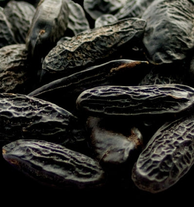 Close-up of tonka beans, showcasing rich texture and deep color, used in perfumery and fragrance creation.