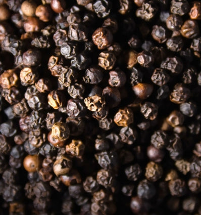 Close-up of black peppercorns, showcasing their rich textures and tones for culinary or fragrance use.